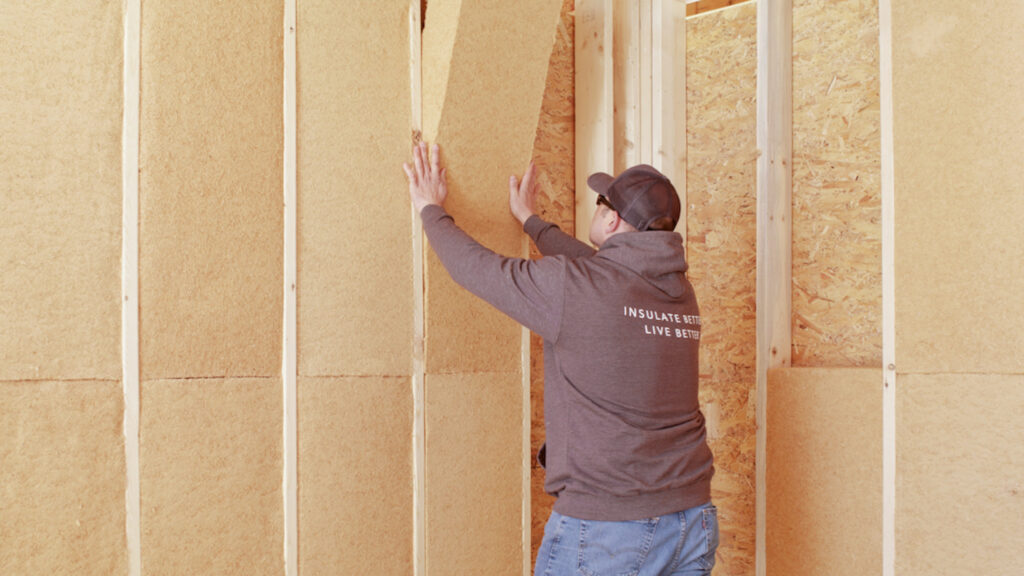 man installing TimberBatt between wall studs